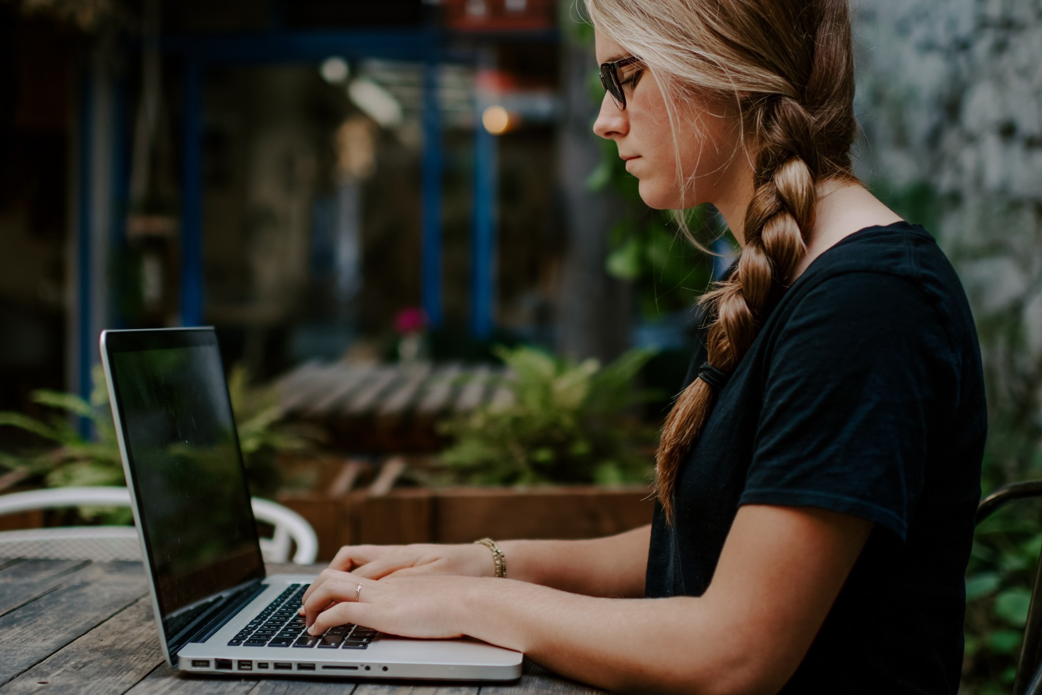 Young person typing on laptop outside