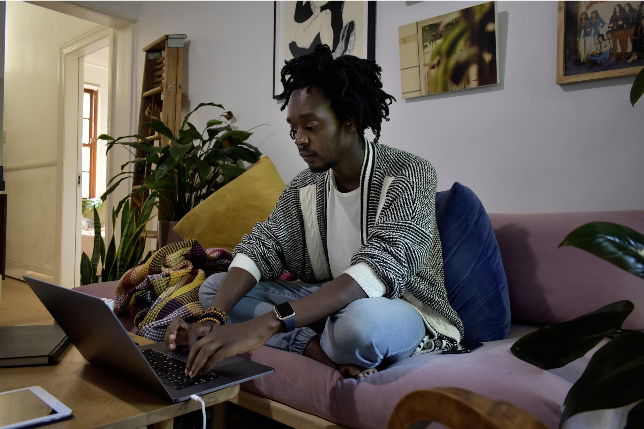 Black millennial with natural hair sitting on a couch and working from home t20 g LNL Pz