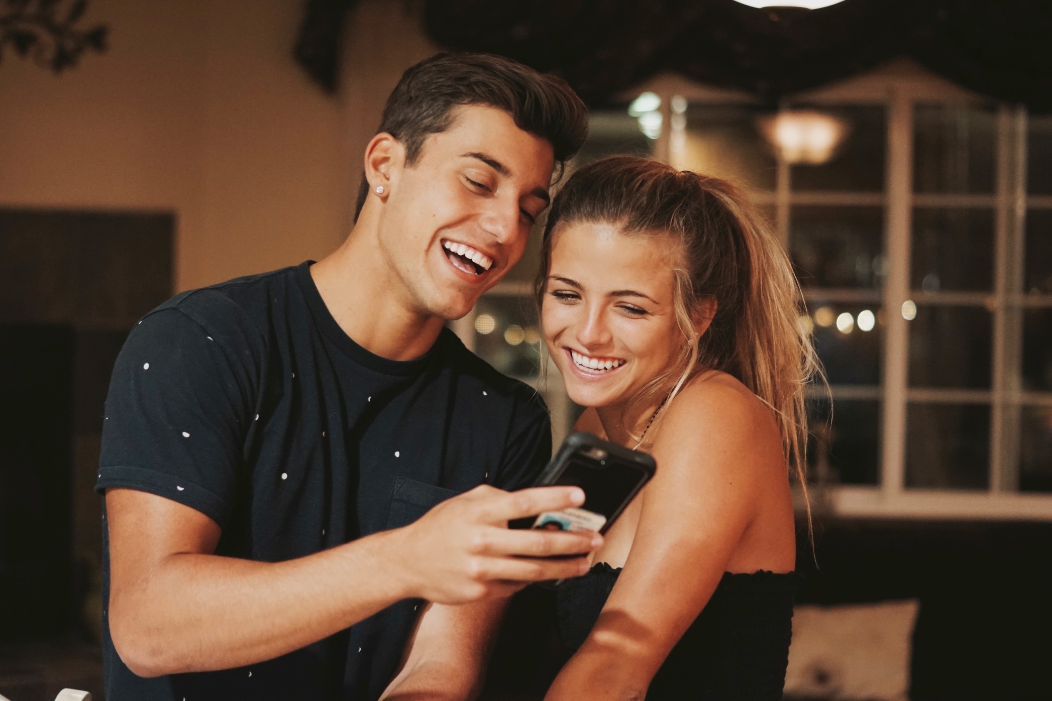 Happy cute couple laughing while watching youtube mobile phone reading a text social media awesome t20 V71dpw