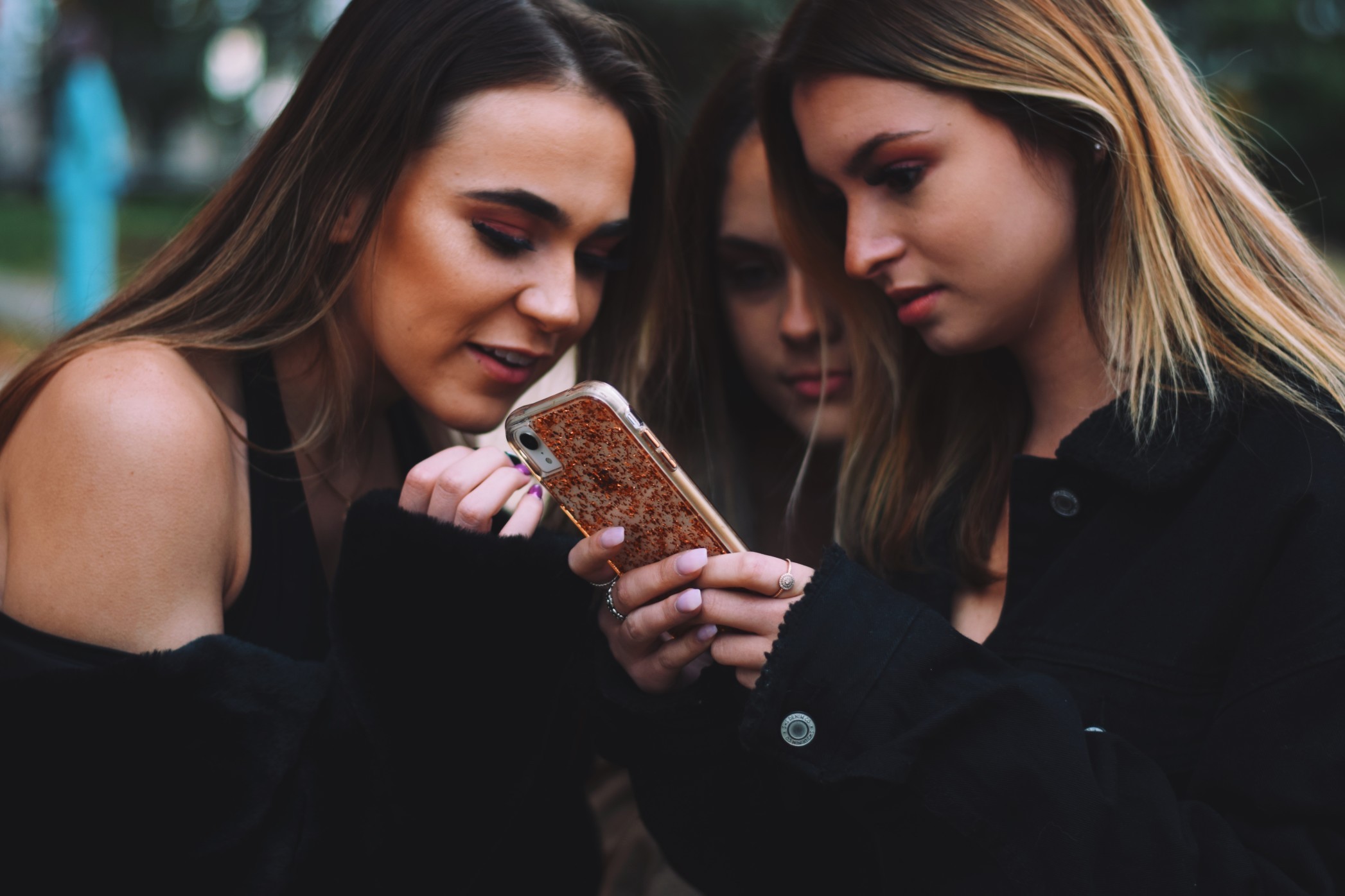 Three girls friends looking at a mobile phone nominated t20 zn Zd7n